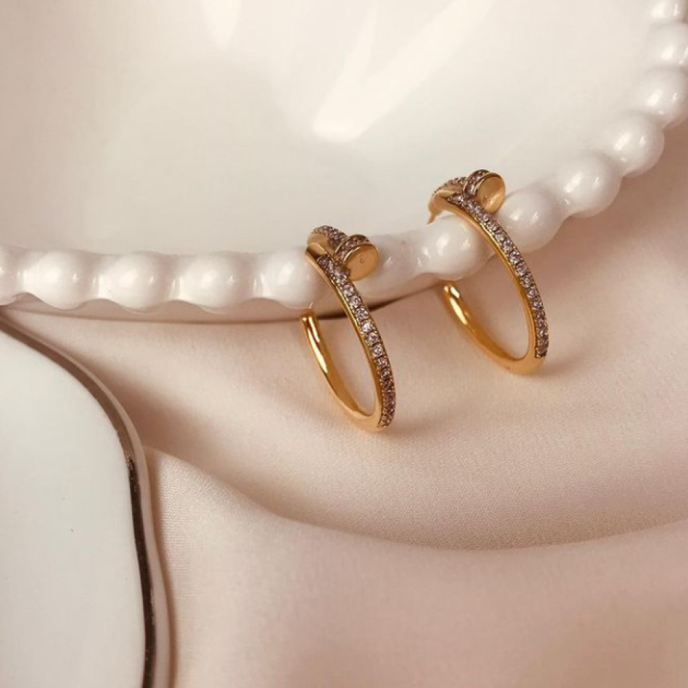Argola em forma de prego cravejada com zircônia folheada a ouro 18k 