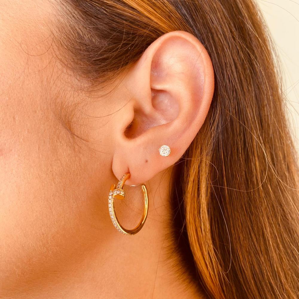 Argola em forma de prego cravejada com zircônia folheada a ouro 18k 